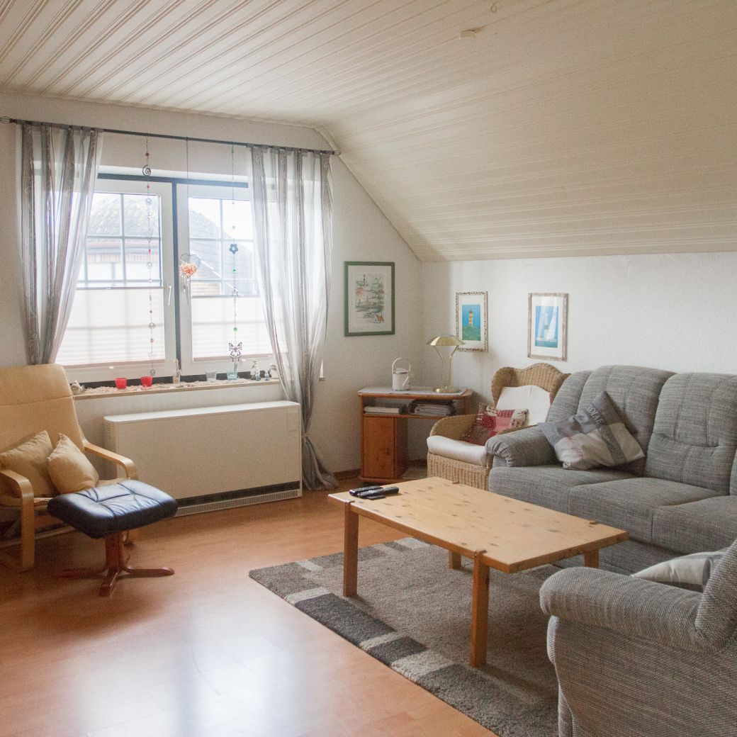 Wohnbereich mit großer Couch, Couchtisch, Sesseln und Fenster