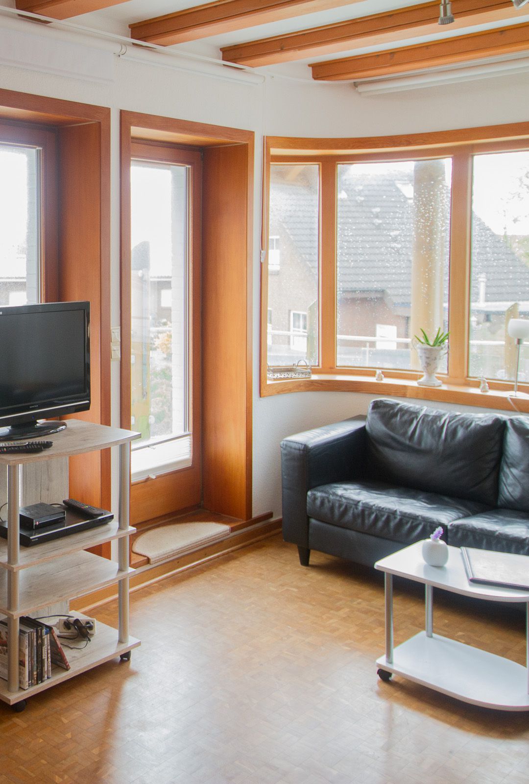 Wohungbereich mit TV und Couch, Panoramafenster & Balkonzugang